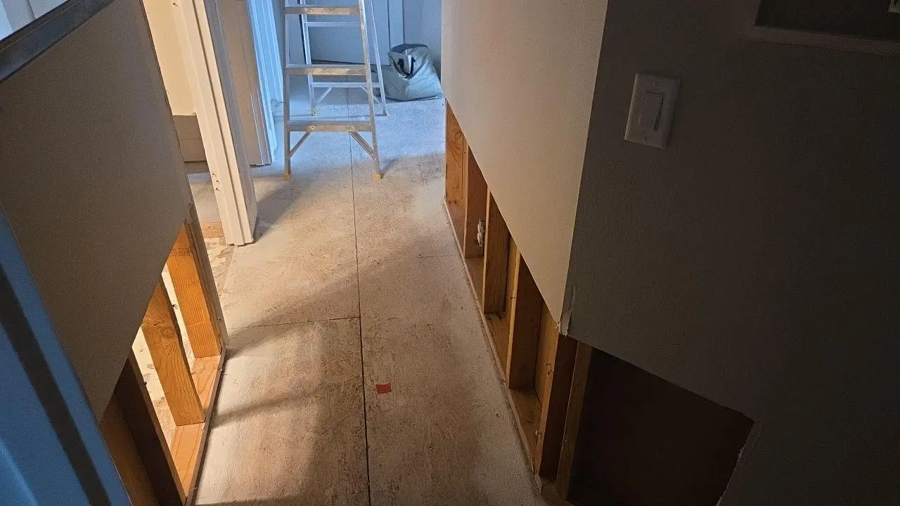 Hallway with exposed subfloor and demo'd drywall